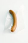 Closeup view of one Frankfurter sausage on white paper — Stock Photo