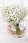 Closeup view of woman holding a bouquet of gypsophila in a vase — Stock Photo