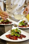 Vista ritagliata di chef drizzling condimento su insalata — Foto stock