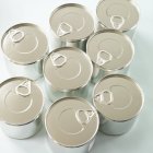 Closeup view of eight food tins on white surface — Stock Photo