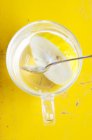 Чай Юдзу в стакане с ложкой на желтой поверхности — стоковое фото