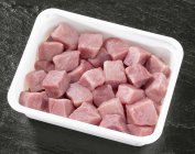 Carne de porco em cubos crus em recipiente de plástico — Fotografia de Stock