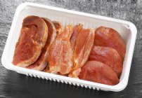 Vue rapprochée de viande de volaille crue assaisonnée dans un récipient en plastique — Photo de stock