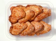 Spicy chicken wings in plastic container — Stock Photo