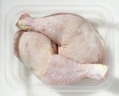 Pernas de frango cru em recipiente de plástico — Fotografia de Stock