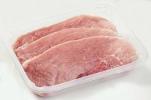 Raw pork escalopes in plastic container — Stock Photo