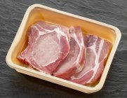 Raw pork chops in plastic container — Stock Photo