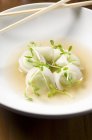 Closeup view of Edamame dumplings in a bowl of broth with chopsticks — Stock Photo