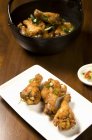 Tambores de pollo al estilo asiático en una bandeja; Pollo en un tazón de fondo - foto de stock