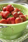 Strawberries in green colander — Stock Photo