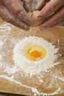 Обрізаний вид рук, що гальмує яйце на купі борошна — стокове фото