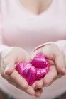 Woman holding heart-shaped chocolates — Stock Photo