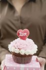 Mão feminina segurando cupcake e presente — Fotografia de Stock