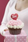 Mujer mano celebración cupcake y regalo - foto de stock