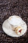 Cup of cappuccino on coffee beans — Stock Photo