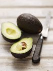Наполовину авокадо с ножом — стоковое фото