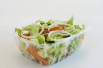 Salada de jardim em um recipiente plástico para ir sobre fundo branco — Fotografia de Stock