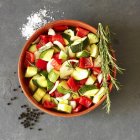 Нарезанные овощи с розмарином в красной миске — стоковое фото