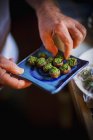 Cropped view of male hands holding and picking spinach-stuffed mushrooms — Stock Photo
