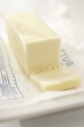 Vista de primer plano de un bloque de mantequilla en rodajas en una envoltura - foto de stock