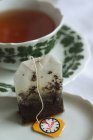 Teabag na frente de uma xícara de chá — Fotografia de Stock