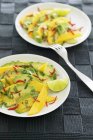 Avocado salad with a mango and lime dressing on white plates with fork — Stock Photo