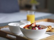 Vista de primer plano de la bandeja de desayuno con ensalada de frutas, pastelería y jugo de naranja - foto de stock