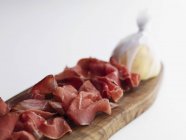 Lonchas de jamón de Parma sobre tabla de madera - foto de stock