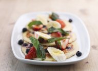 Pancakes with fruit salad and mint — Stock Photo