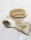 Elevated view of a bowl of porridge oats and a vintage spoon — Stock Photo