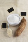 Vista elevata delle radici di manioca con farina, pala e targhette bianche nere — Foto stock