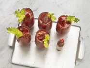 Cinco Bloody Marys adornadas con apio en una bandeja - foto de stock