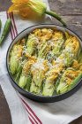 Stuffed courgette flowers in a baking dish over towel  over wooden surface — Stock Photo