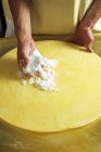 Wheel of cheese being rubbed — Stock Photo
