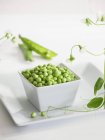 Bowl of fresh peas with pods — Stock Photo