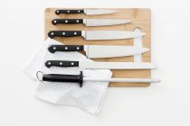 Various knives and a sharpening steel on a chopping board — Stock Photo