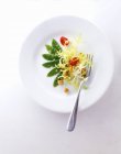 Frisee lettuce with mange tout, cherry tomatoes and croutons on white plate with fork — Stock Photo