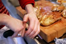 Vista de cerca de la persona que corta pollo asado con un cuchillo - foto de stock
