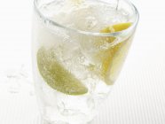 Closeup view of fizzy drink with slices of citrus fruit — Stock Photo