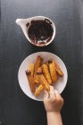 Vista superior de Churros con salsa de chocolate y mano de niño tomando uno - foto de stock
