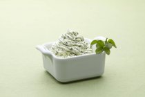 Uma tigela de manteiga de ervas em uma superfície verde clara — Fotografia de Stock
