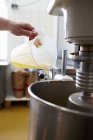 Closeup view of a hand adding oil to a mixer in a bakery — Stock Photo