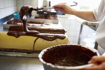 Обрізаний вид кухаря, що покриває торт шоколадною глазур'ю — стокове фото