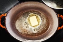 Vista superior de una pieza de mantequilla derretida en una olla - foto de stock