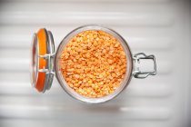 Closeup top view of red lentils in an opened flip-top jar — Stock Photo