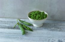 Bowl of fresh peas and pods — Stock Photo