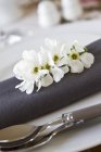 Closeup view of place setting with a grey napkin and fruit blossoms — Stock Photo