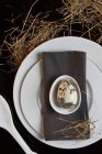 Вид сверху на место Пасхи с серой салфеткой и художественно окрашенным яйцом — стоковое фото