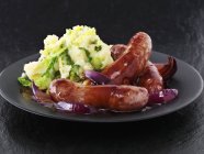 Sausages with red onion gravy — Stock Photo