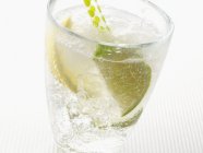 Closeup view of sparkling mineral water with ice cubes, lemon and lime wedges — Stock Photo